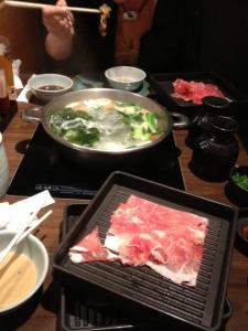 Broth and veggies boiling away on the table, with the thin slices of meat ready to go.